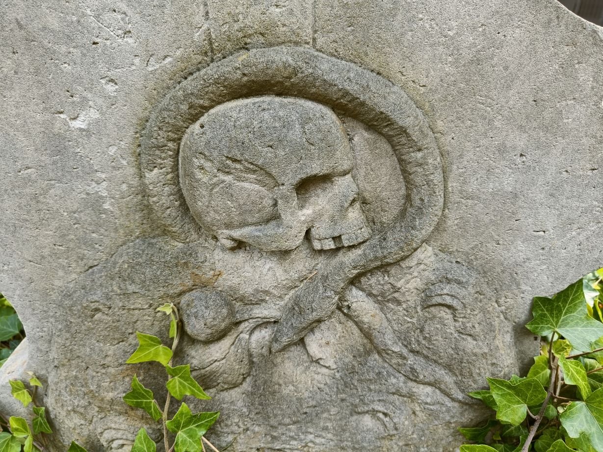 Totenkopf mit Schlange an einem Grabstein